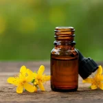 Frasco de aceite de hipérico junto a flores amarillas y un símbolo de advertencia sobre sus contraindicaciones